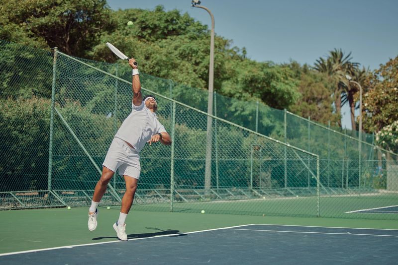 Fitness, tennis and jump, man on court with bat jumping to hit ball, outdoor fun at practice match. Health, wellness and happy summer workout, sports player and exercise in playing game with racket.