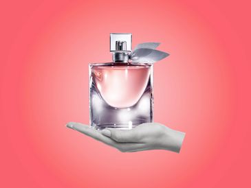 Elegant perfume bottle with a soft pink background held by a hand.