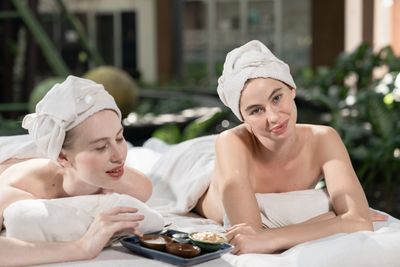 Two women relaxing with towels on their heads, enjoying spa treatments together.