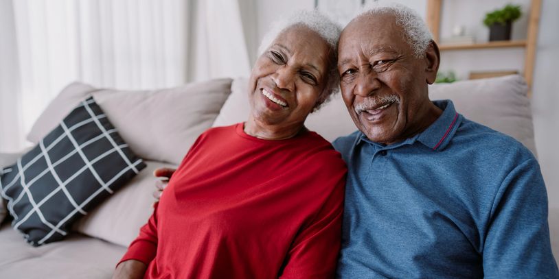 Smiling elderly couple sitting close together on a cozy couch.