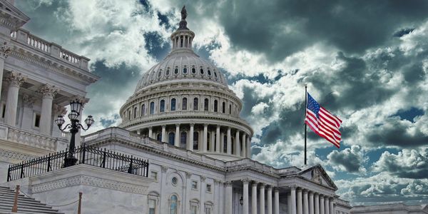 US Capitol building with dramatic sky and flag.