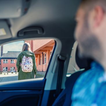 Person watching another with a backpack through a car window.