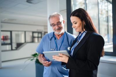 Doctor and businesswoman reviewing tablet content.