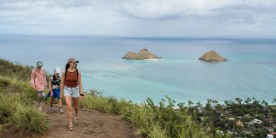 Three people hiking with ocean and islands in background.