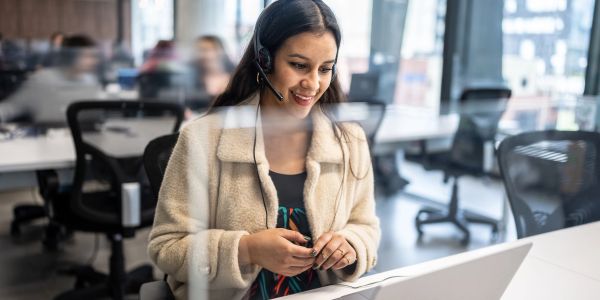 Woman customer service representative smiling at laptop.
