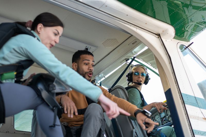 Paratroopers with parachutes on their backs board the plane. In the background, a female pilot prepares the plane for takeoff. They joke, hug each other, give each other high fives and encourage each other.