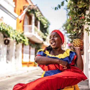 Woman in colorful dress holding a pineapple.