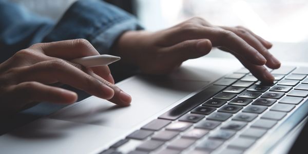Person using a laptop with a stylus pen in hand.