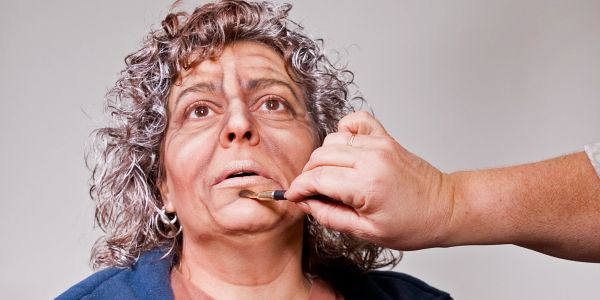 Makeup artist applying prosthetic makeup on woman's face.