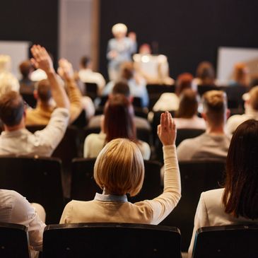 Audience members raising hands during a conference or seminar. transformación de negocios