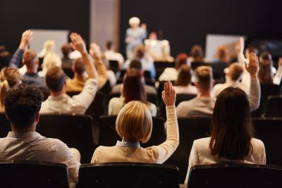 Audience members raising hands during a conference or seminar.