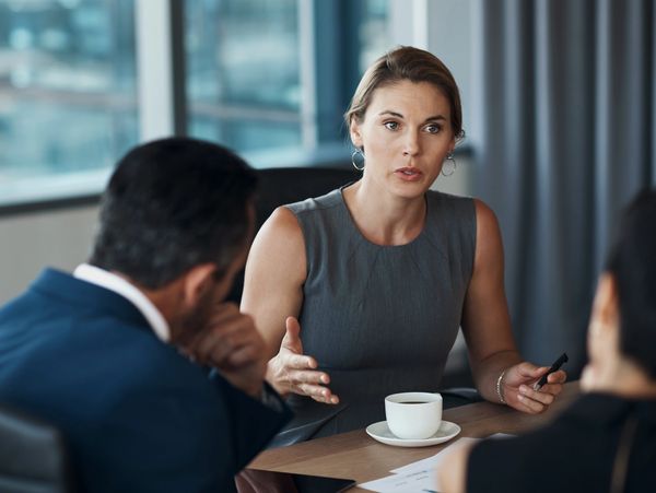 A professional woman passionately discusses a point in a business meeting.