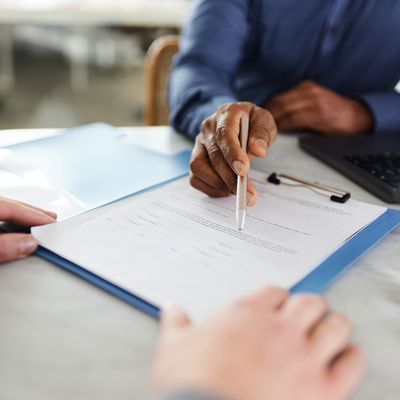 Hände mit Stift über einem Vertrag bei einer Besprechung