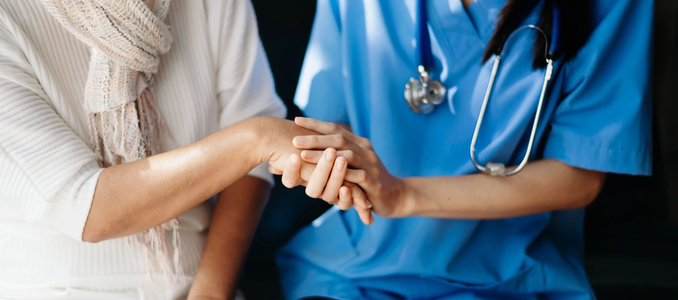 A healthcare professional holding a patient's hand in a comforting gesture.