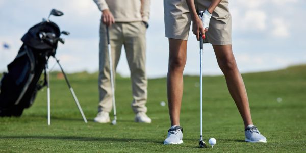 Two people playing golf on a green course.