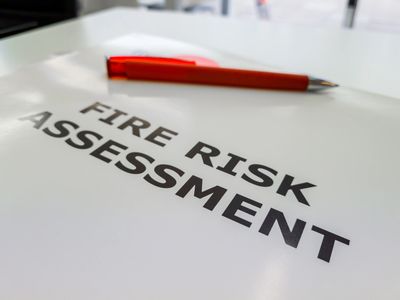A fire risk assessment document with a red pen on top.