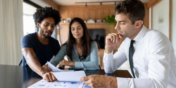 Three people discussing documents at a table.