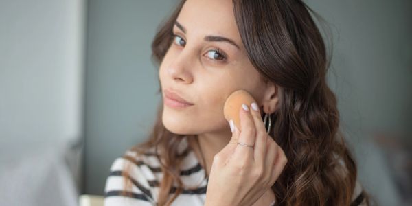 Woman applying makeup with a sponge.