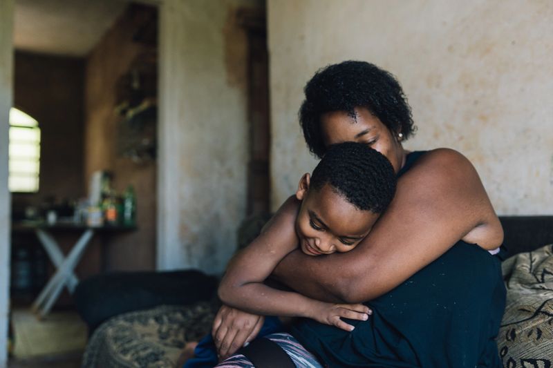 Mother and daughter are lying on a comfortable sofa, covered by a soft blanket, enjoying a quiet and intimate moment together, exchanging loving smiles and strengthening their bond