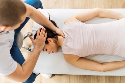 Chiropractor adjusting the neck of a patient with a headache on an adjusting table.