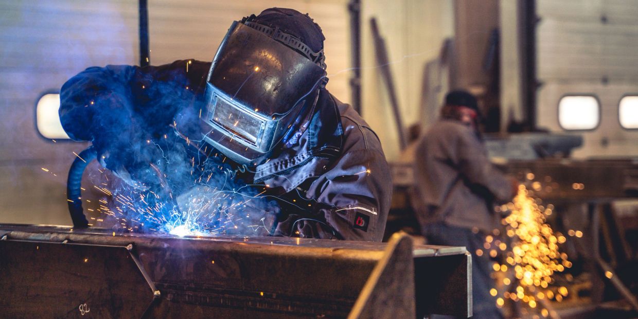 Welder working with sparks flying in workshop.