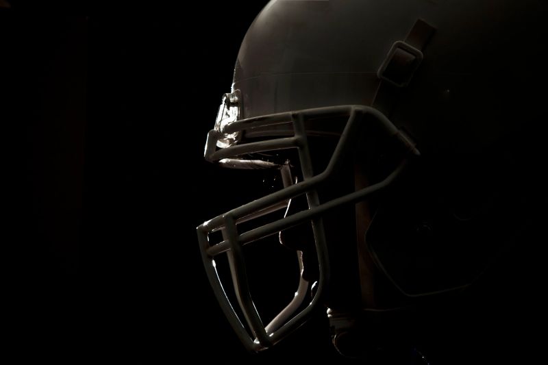 Closeup of side of a football helmet on a black background.