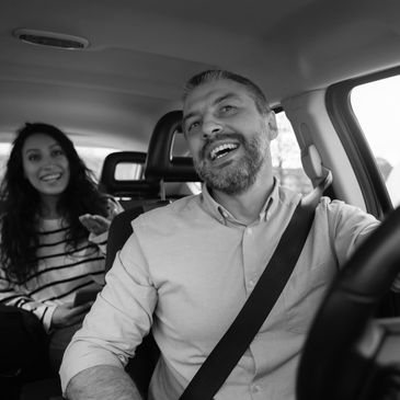 Driver smiling with a passenger in the backseat who is also smiling