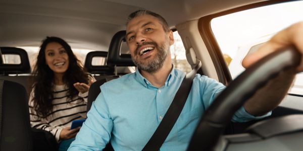 Happy man driving car with woman passenger.