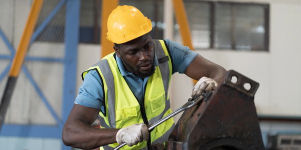 Worker in safety gear operating machinery in an industrial setting.