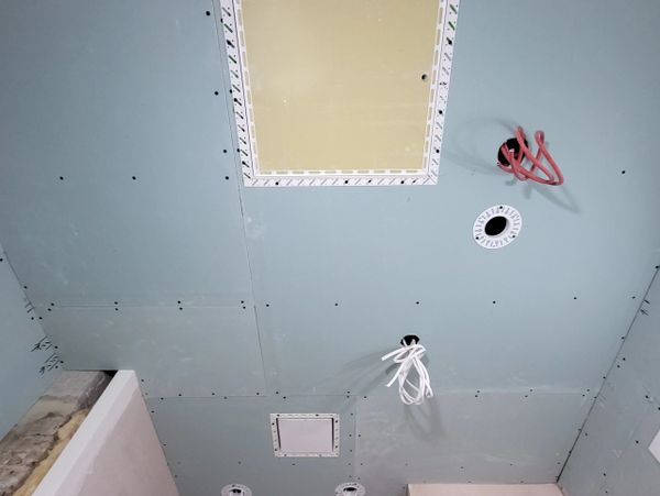 Ceiling under construction with electrical wiring and access panels.