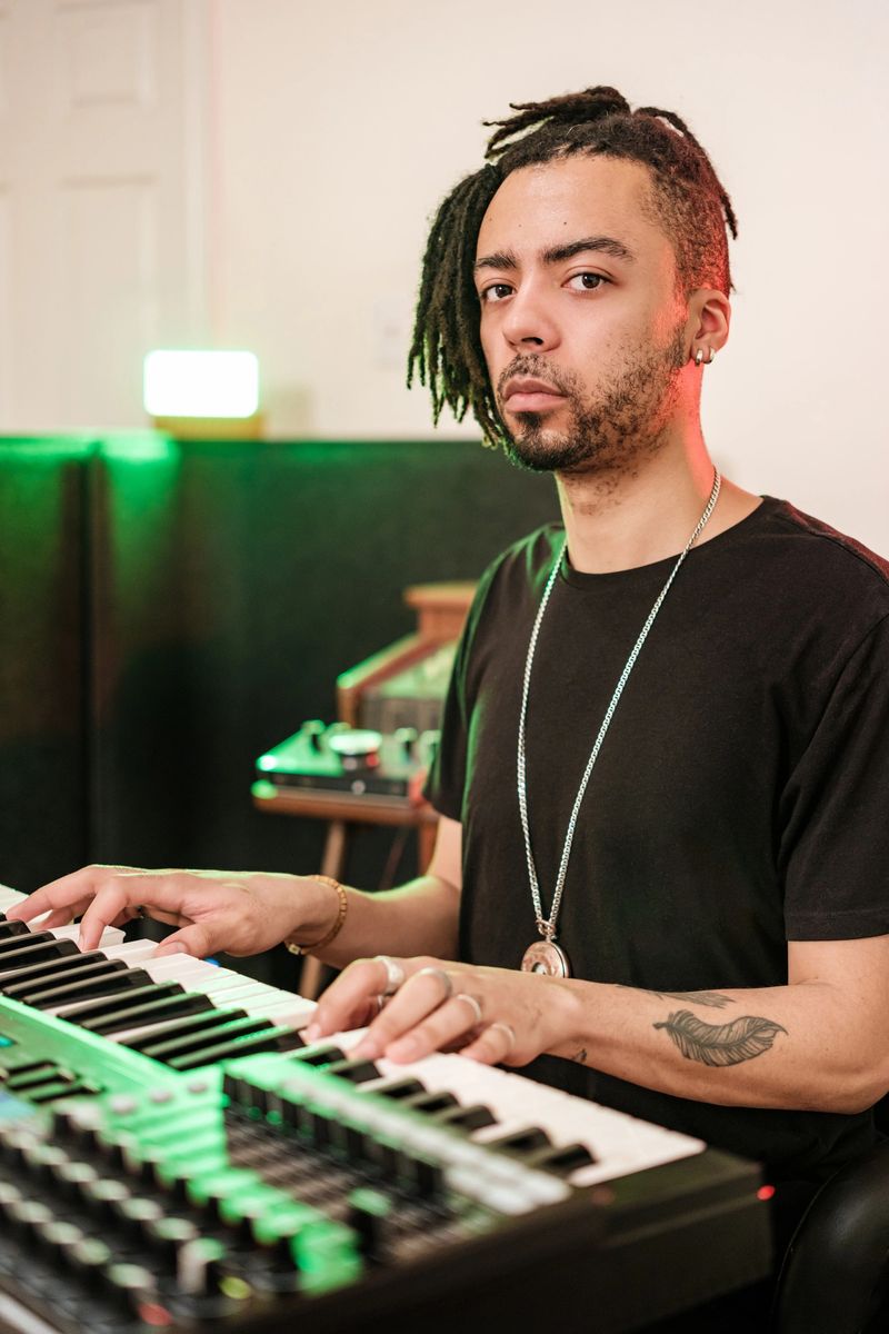 Male mixed race Musician practising at home recording studio. He is dressed in casual black outfit .  Interior of home recording studio.