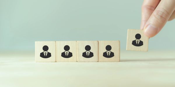 Wooden blocks with businesspeople icons, one block being moved.