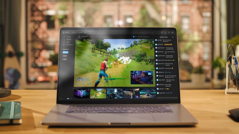 Laptop Computer Display with Game Live Streaming Platform Standing on Wooden Table with a Notebook in Living Room. Famous Influencer Trying a Newly Released Game Online and Sharing his Screen