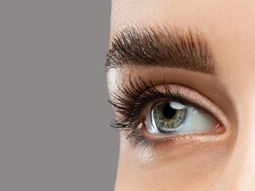 Close-up of a blue-green eye with long lashes and thick eyebrow.
