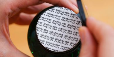 Cierre de protección en frasco verde siendo retirado.