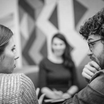 Three people involved in a serious conversation indoors.