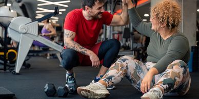Man and woman high-five at gym after workout, celebrating success.