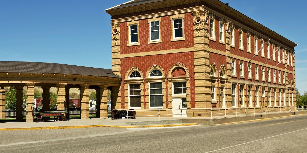 Historic brick train depot building with arched windows and covered platform.