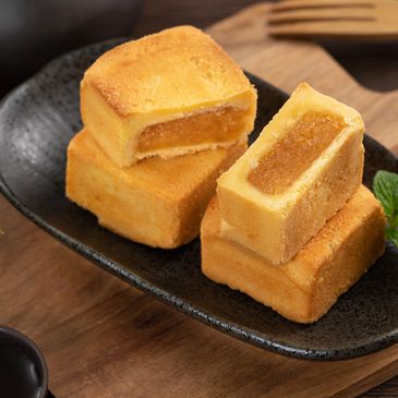 Golden pineapple cakes stacked on a black plate.