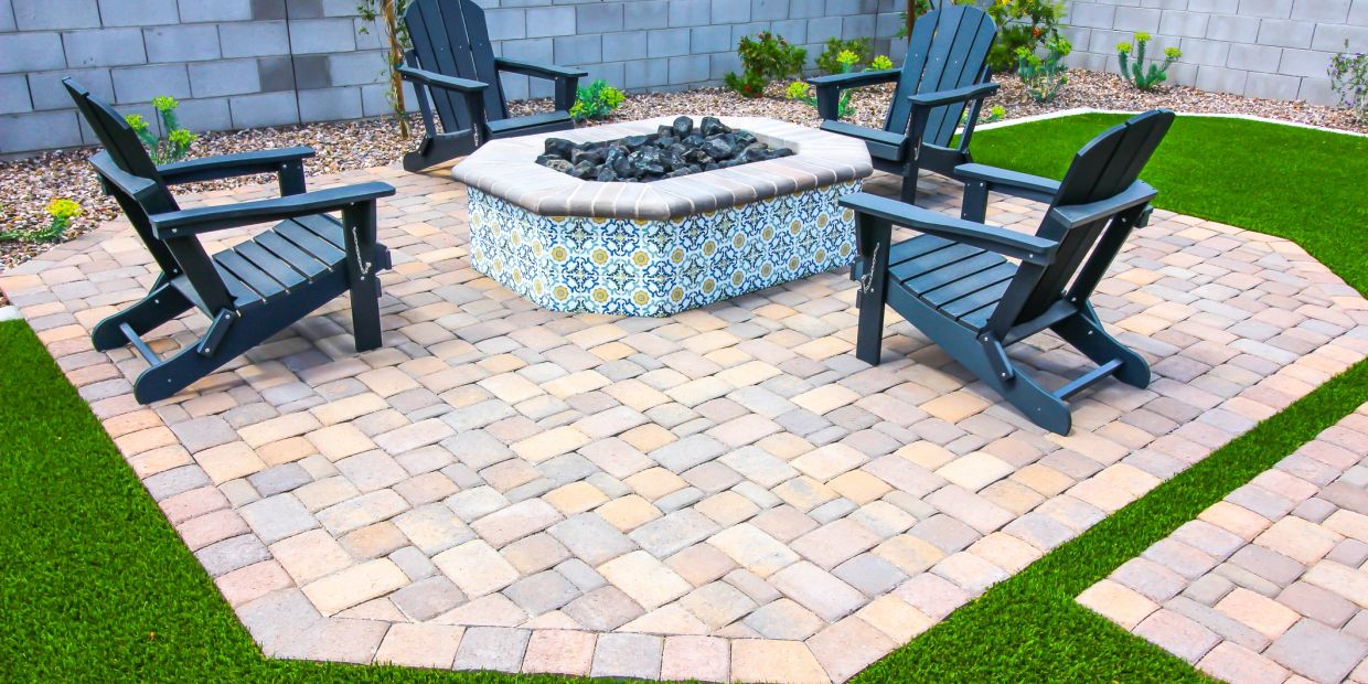 Outdoor patio with four black chairs around a decorative fire pit.