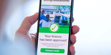 A phone screen shows a finance approval message for a house loan.
