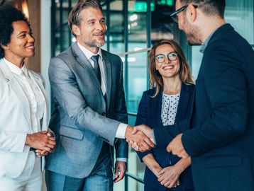 Businesspeople shaking hands and smiling in an office.