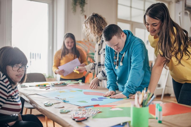 People with down syndrome and cerebral palsy doing an art project with help with assistants and animators.Disability health care art workshop.