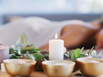 Lit candles and spa bowls with a person relaxing in the background.