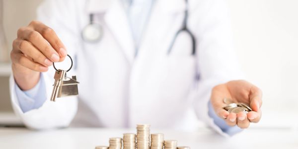 Doctor holding house key and coins symbolizing real estate investment or financial planning.