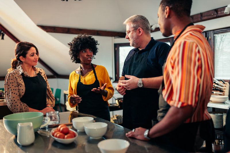 A chef is talking to his diverse students in a private cooking class at home.