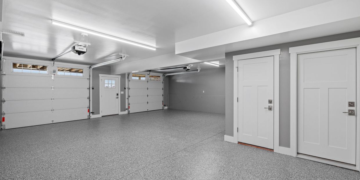Spacious clean garage with two large doors and extra entry doors.