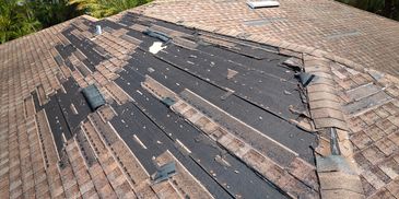 A roof with missing and damaged shingles exposing the underlayment.