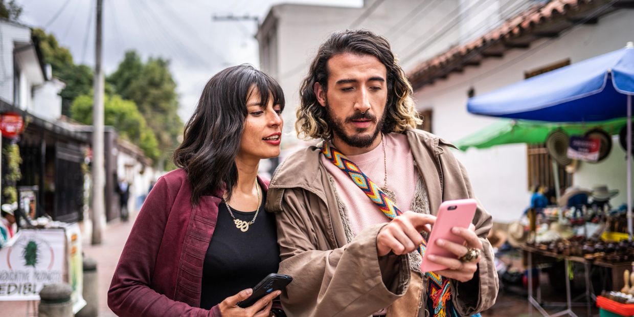 Two people looking at a phone outdoors.
