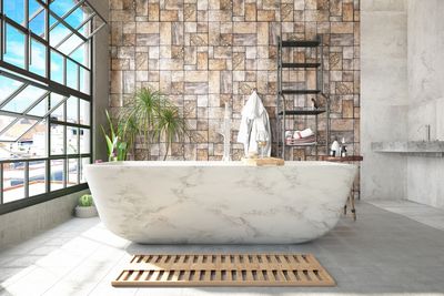 Modern bathroom with a marble bathtub and stone accent wall.